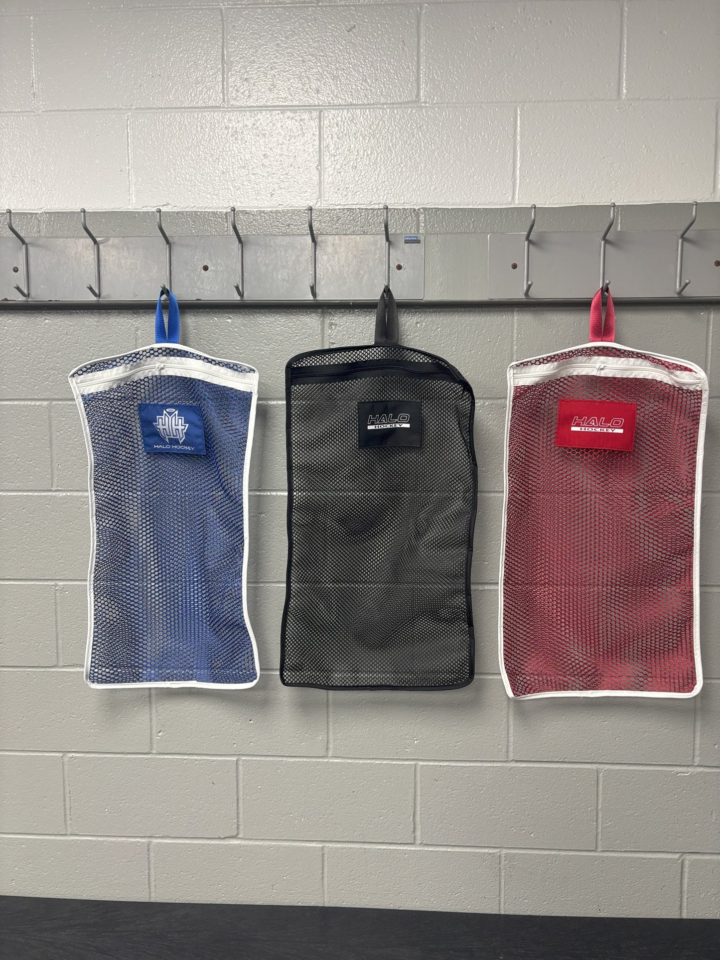 All 3 color options of Halo Hockey Stinky Boy Laundry Bags shown hung side by side on locker room hooks