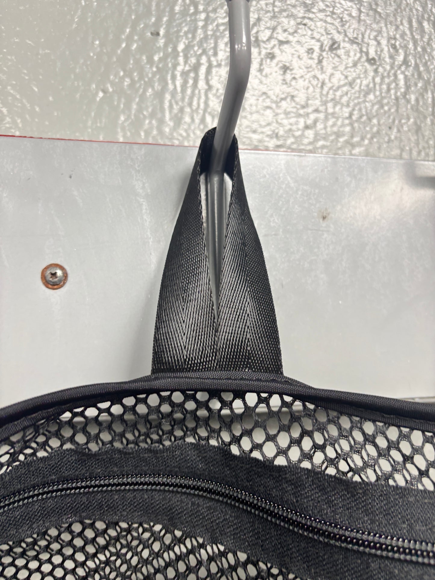 Closeup view of the hang loop on a black Halo Hockey Stinky Boy laundry bag shown hung from a wall hook