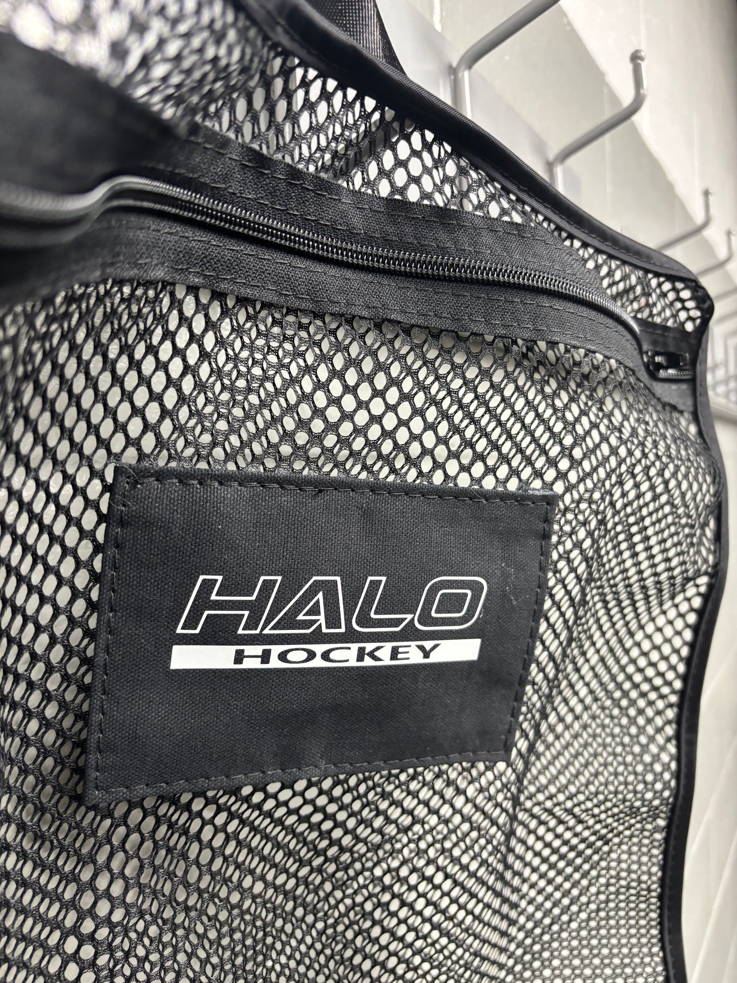 Tilted closeup of Halo Hockey Stinky Boy laundry bag in black color option showing the zipper, logo panel area and stitching detail