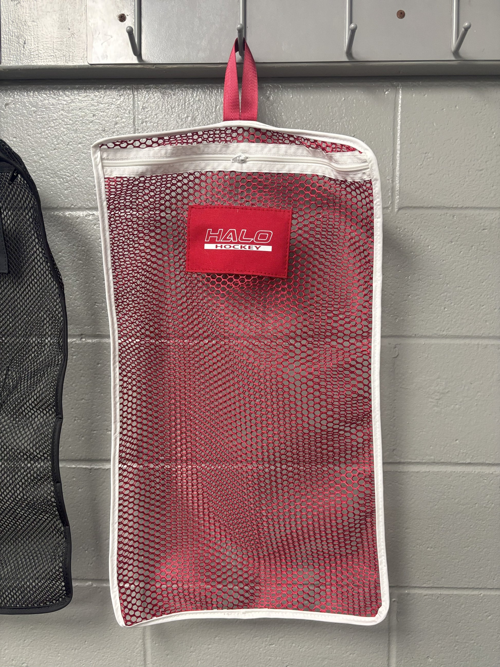 Halo Hockey Stinky Boy laundry bag in red shown hung on a locker room wall hooks