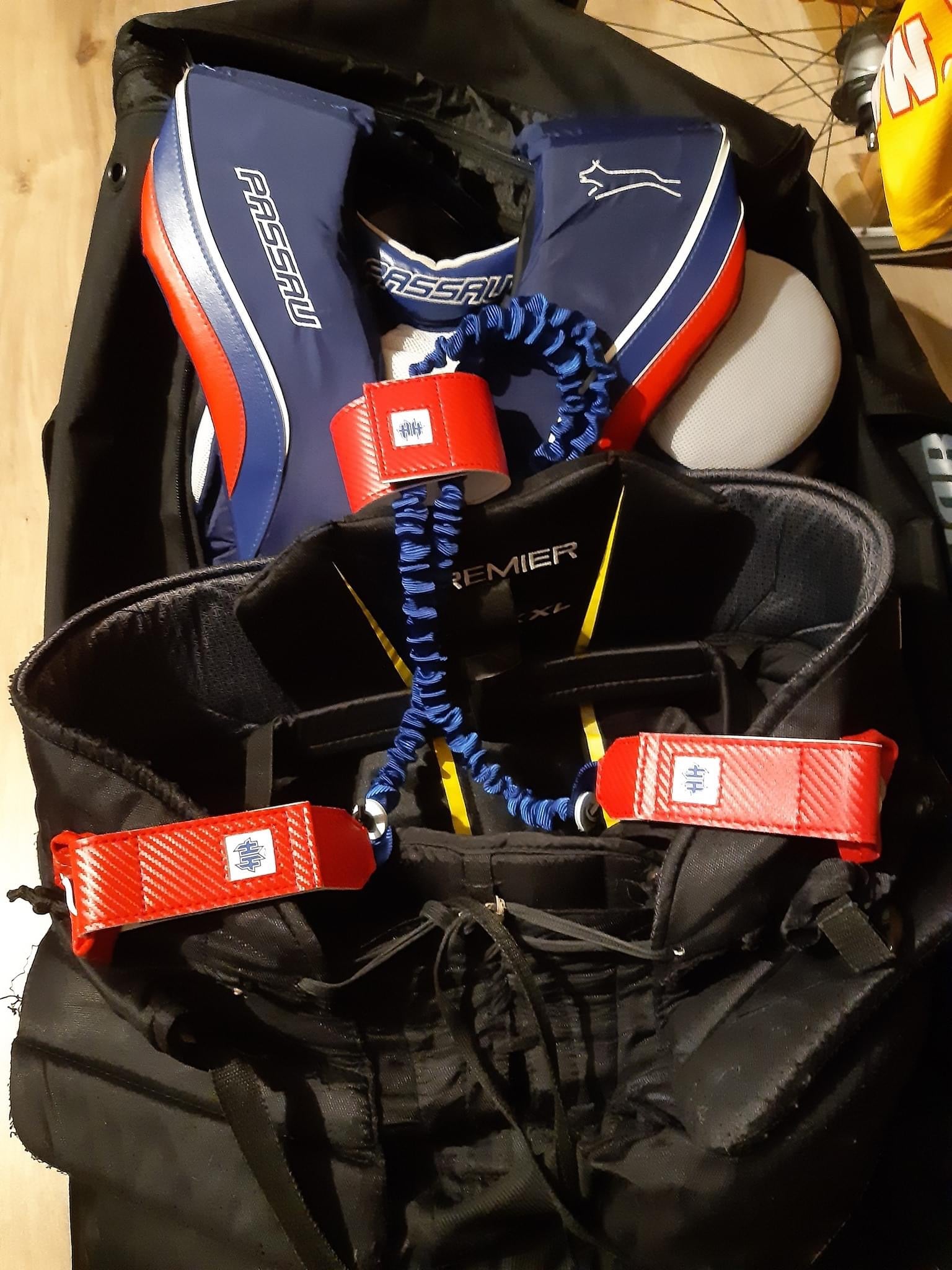 Red carbon fiber Halo Hockey Suspenders 2.0 bungee goalie suspenders with blue logos installed on CCm Premier goalie pants